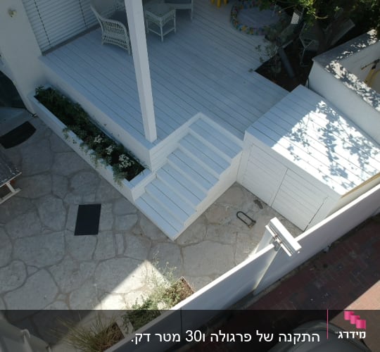 מרפסת עץ לבנה עם מדרגות וצמחייה